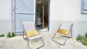 Two lounge chairs with cushions outside a building with a sliding door.