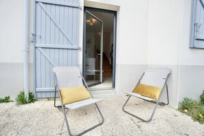 Two lounge chairs with cushions outside a building with a sliding door.