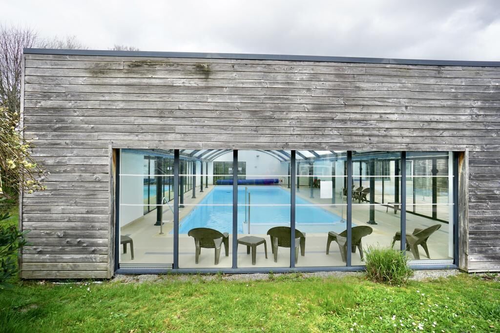 A modern building with a glass facade overlooking a swimming pool area.