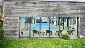 A modern building with a glass facade overlooking a swimming pool area.