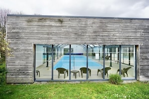 A modern building with a glass facade overlooking a swimming pool area.