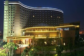 Un hotel de varios pisos con fachada curva y un área de entrada destacada.