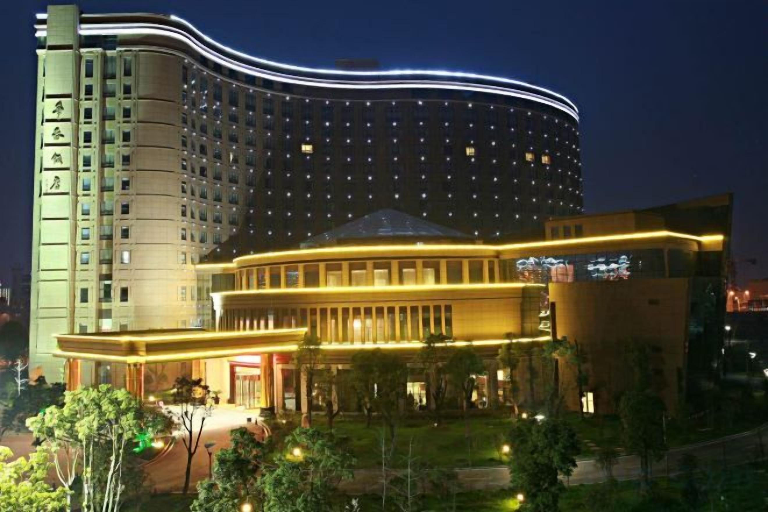 Un hotel con fachada curva, varios pisos y un área de entrada bien iluminada.