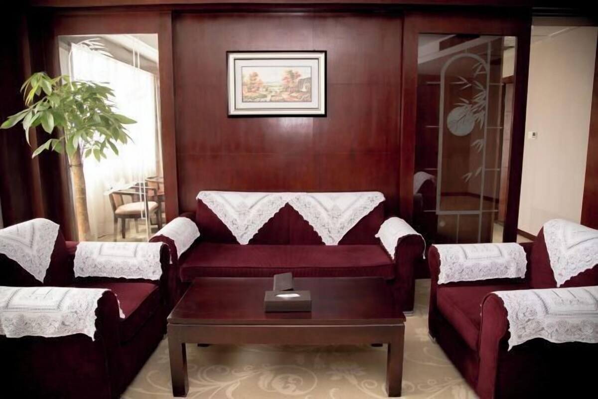 A room with a dark wooden wall, a framed picture, and a large plant.