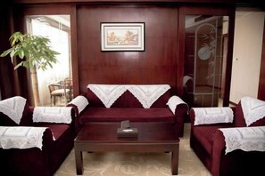 A room with a dark wooden wall, a framed picture, and a large plant. - Huatai Hotel (Tianmen)