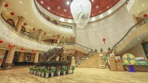 A multi-level atrium with a central sculpture, potted plants, and a large chandelier. - Huatai Hotel (Tianmen)