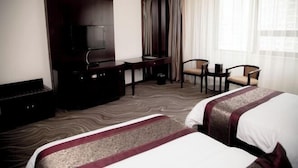 A hotel room with two beds, a desk, a television, and a seating area with chairs. - Huatai Hotel (Tianmen)