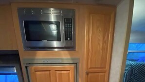 Eine kleine Küche mit Mikrowelle, Backofen und Holzschränken.