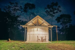 Una estructura pequeña, al aire libre, con techo triangular y zona de estar cubierta.