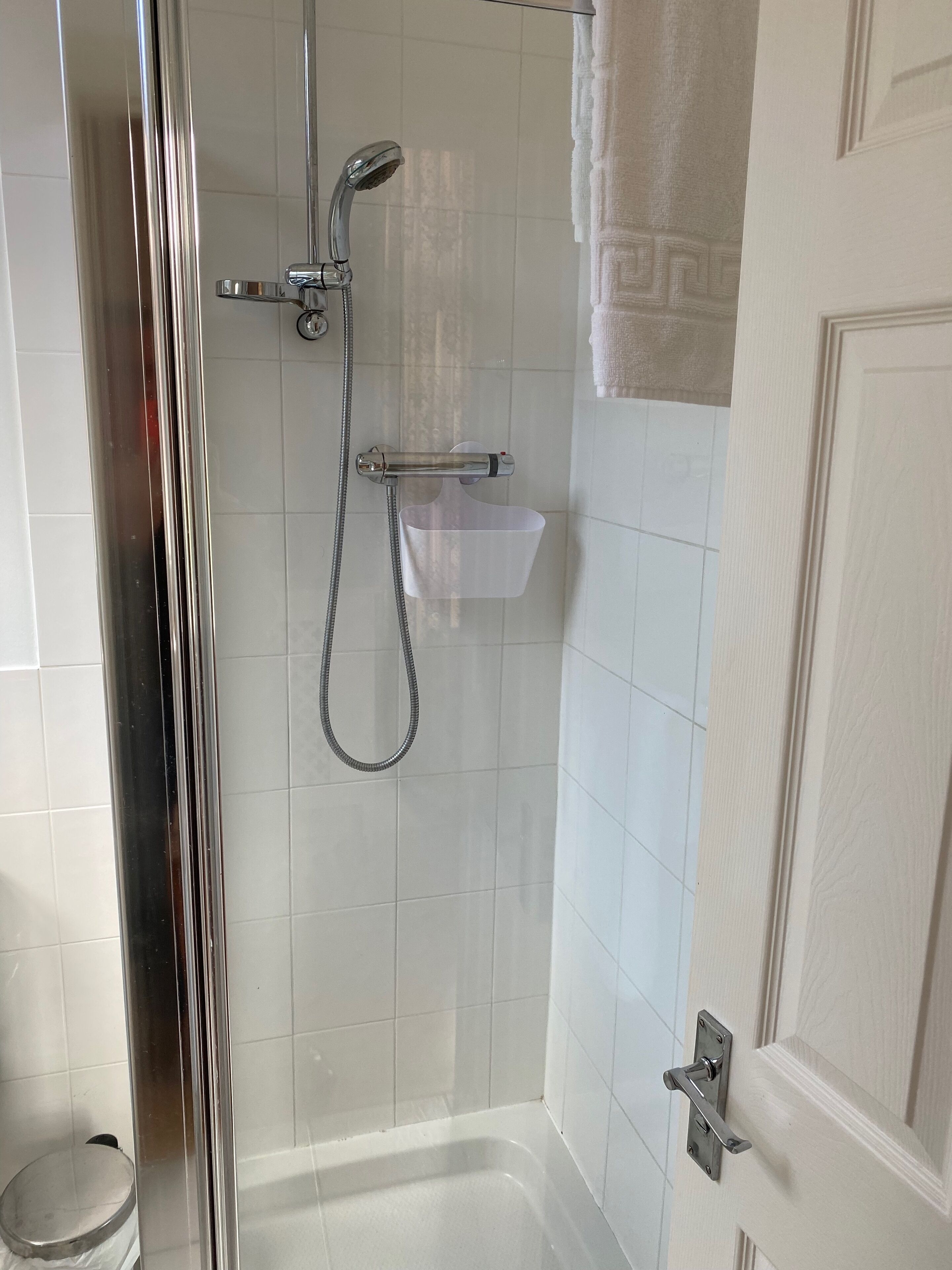 Un baño con ducha, un lavamanos blanco y una puerta.