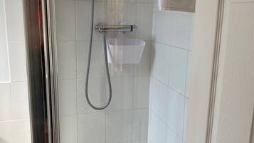 A bathroom with a shower, a white sink, and a door.