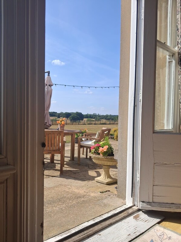 An open door leading to an outdoor patio with a table, chairs, and potted plants. - Coundon Lodge (Coventry)