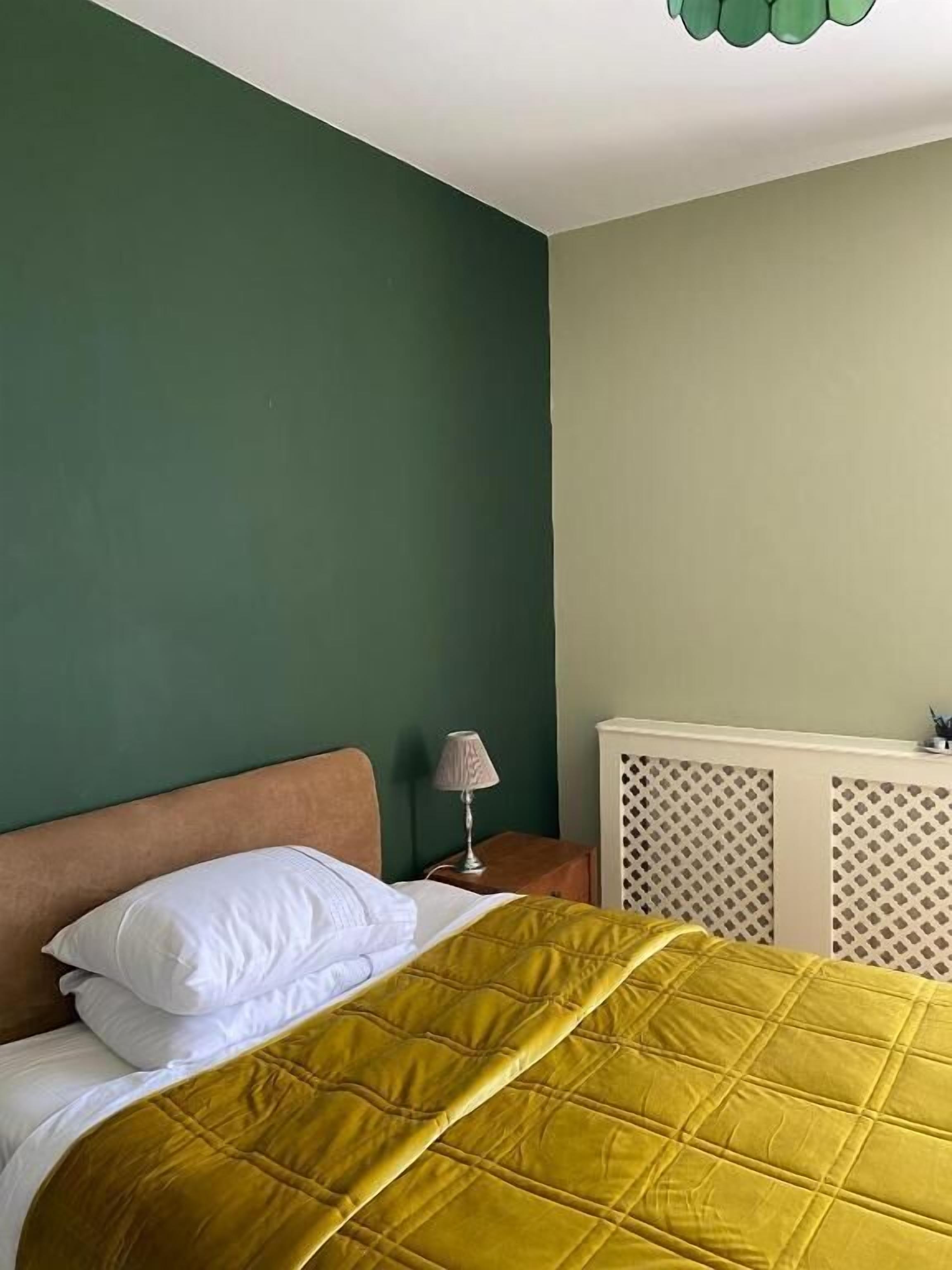 Une chambre à coucher avec un lit, une table de chevet, une lampe et un radiateur.