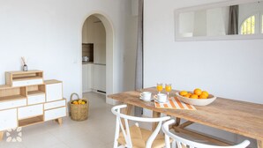 Une cuisine moderne avec des meubles blancs et une table en bois mise pour le petit-déjeuner.