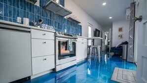 A modern kitchen with white cabinets, a built-in oven, and blue-tiled backsplash.