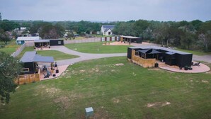 A spacious outdoor area with a covered seating area, a small building, and a large black structure.