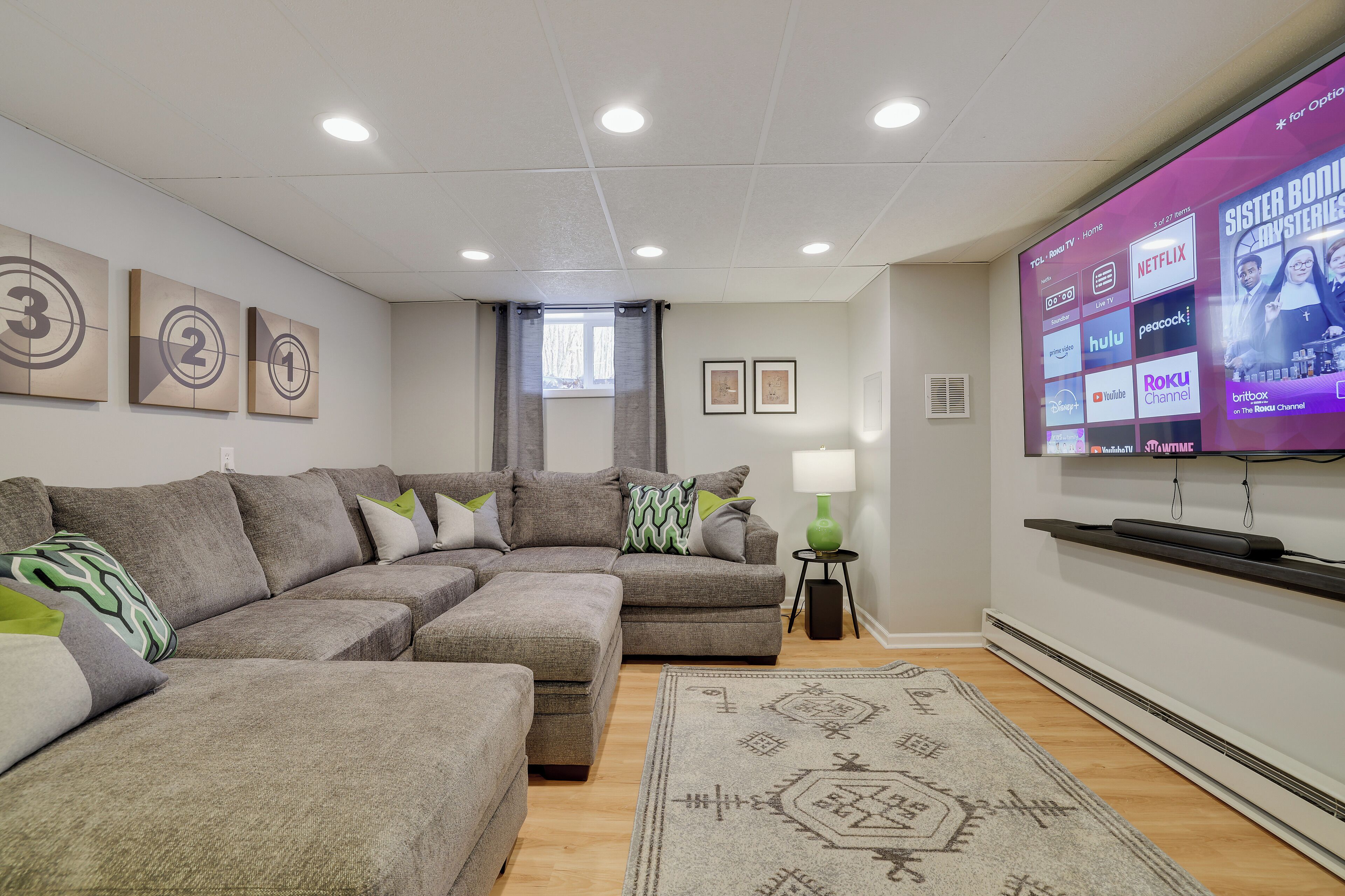 A modern living room with a sectional sofa, a flat-screen TV, and a decorative rug.