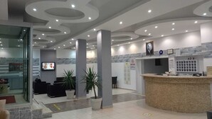 A modern reception area with a curved reception desk, seating area with sofas, and potted plants. - BODRUM LOTUS LINE HOTEL (Bodrum)