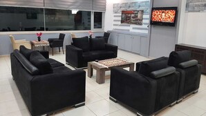 A modern lounge area with black sofas, a wooden coffee table, and a TV mounted on the wall. - BODRUM LOTUS LINE HOTEL (Bodrum)