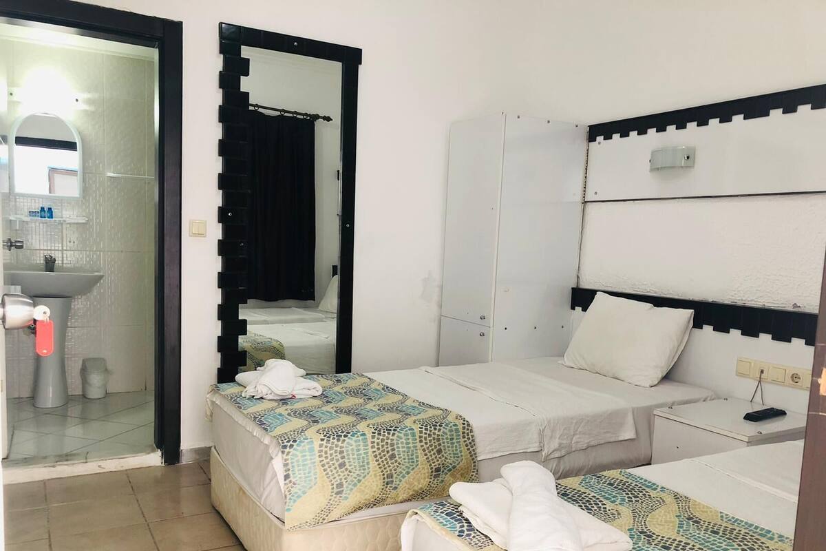 A hotel room with two beds, a bathroom, and a wardrobe.