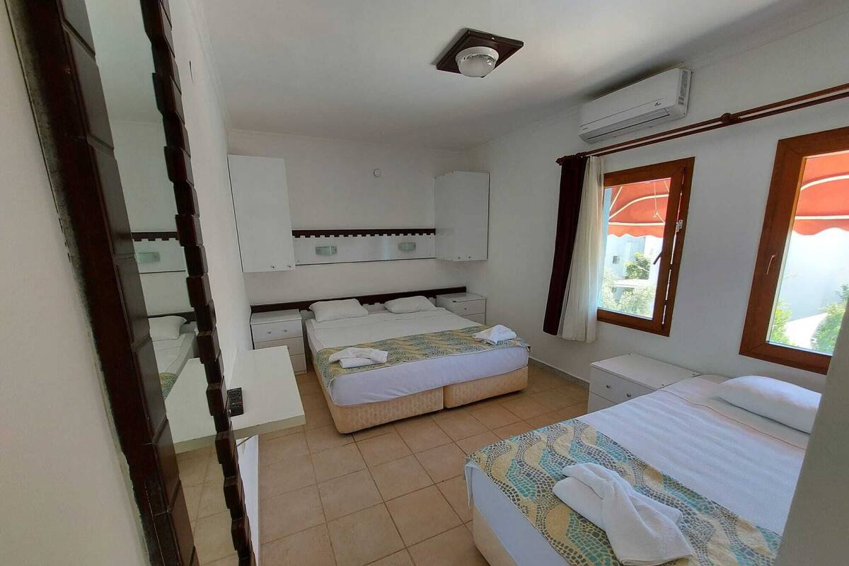 A bedroom with a bed, a bedside table, a wardrobe, and a window.