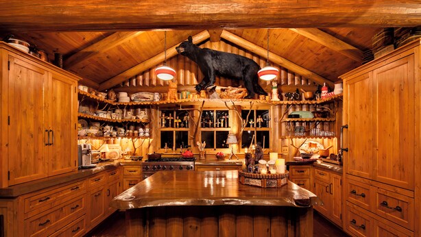 Una cocina rústica de madera con una escultura de oso en el techo, armarios de madera y una isla grande.