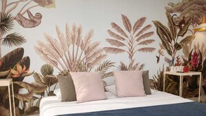 Une chambre à coucher avec un lit, une table de chevet, une lampe et une fresque murale.
