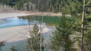 A natural landscape with a river, dense forest, and a clear sky. - Adventure Base Camp #1 (Hungry Horse)