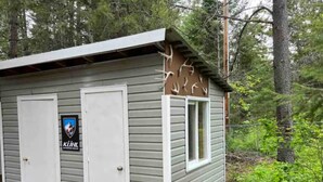 Une petite cabane à un seul étage, avec un toit en métal, deux portes et une fenêtre.