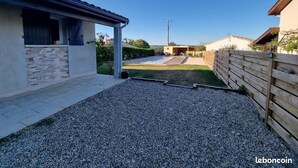 A residential property with a gravel driveway, a covered patio, and a wooden fence. - Villa ‘leticas’, its Private Pool in the Sun of Lot et Garonne (Prayssas)