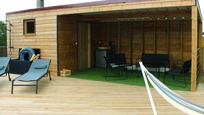 A wooden cabin with a covered patio area, two lounge chairs, a hammock, and a tire storage. - Villa ‘leticas’, its Private Pool in the Sun of Lot et Garonne (Prayssas)