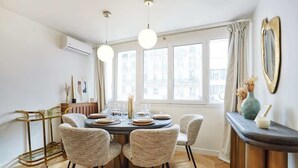 A dining area with a round table, six chairs, and a gold-framed side table. - Apartment in the Center of Paris (Paris)