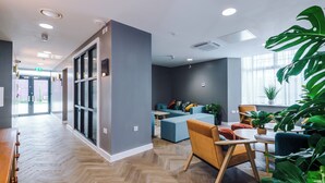 Un interior moderno con suelo de espiga, una zona de estar con sofá y sillones, y un ventanal con plantas.
