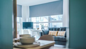 Una sala de estar moderna con un sofá gris, una mesa de centro y una televisión.