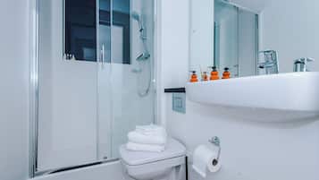 A modern bathroom with a glass-enclosed shower, a white toilet, and a sink with toiletries.