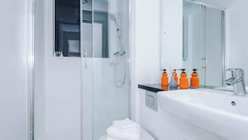 A modern bathroom with a glass-enclosed shower, a white sink, and a large mirror.