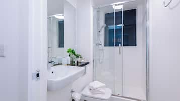 A modern bathroom with a glass-enclosed shower, a white sink, and a toilet.