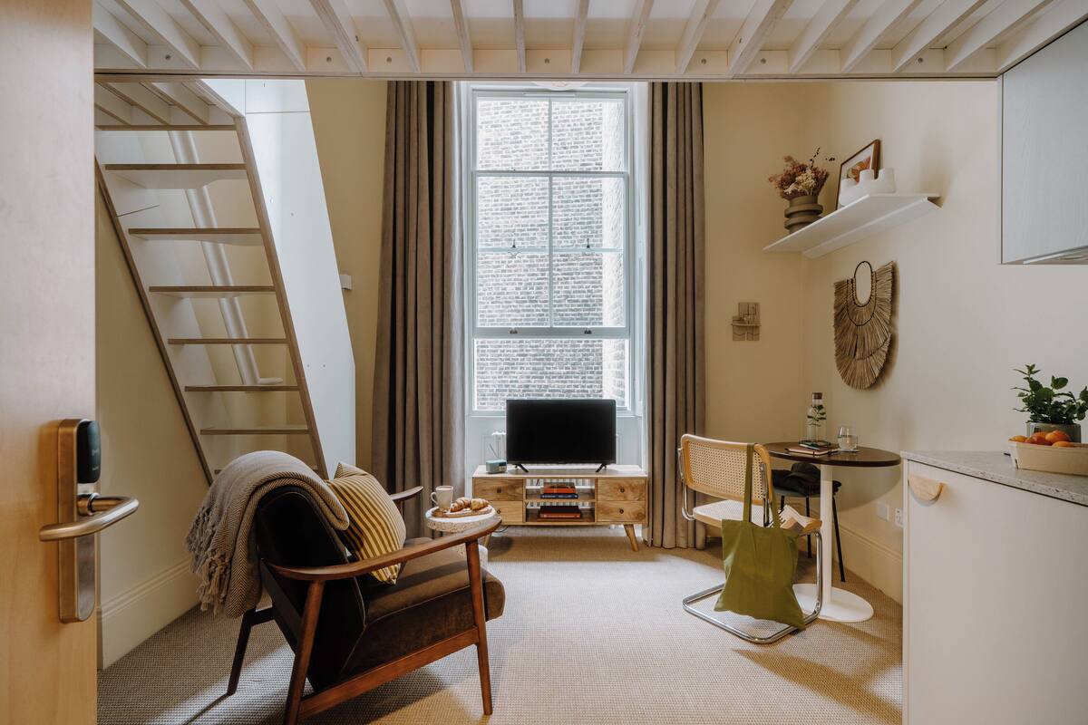 A cozy living room with a sofa, a coffee table, a TV, and a staircase.