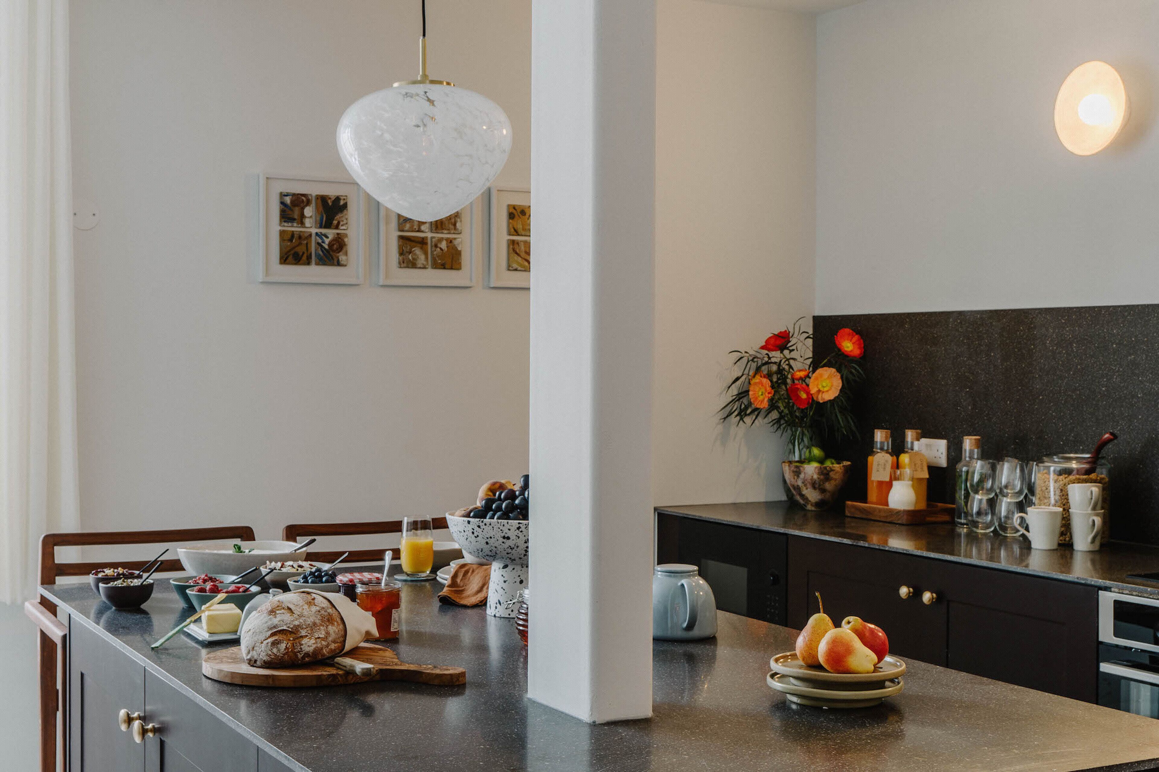A modern kitchen with a marble countertop, a dining area with a wooden table, and a black backsplash.