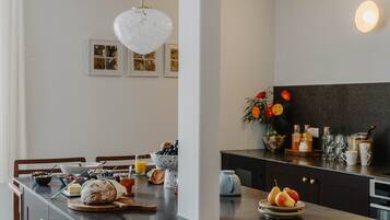 A modern kitchen with a marble countertop, a dining area with a wooden table, and a black backsplash.