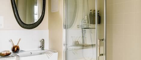 A bathroom with a glass-enclosed shower, a white sink with a mirror above it, and a toilet.