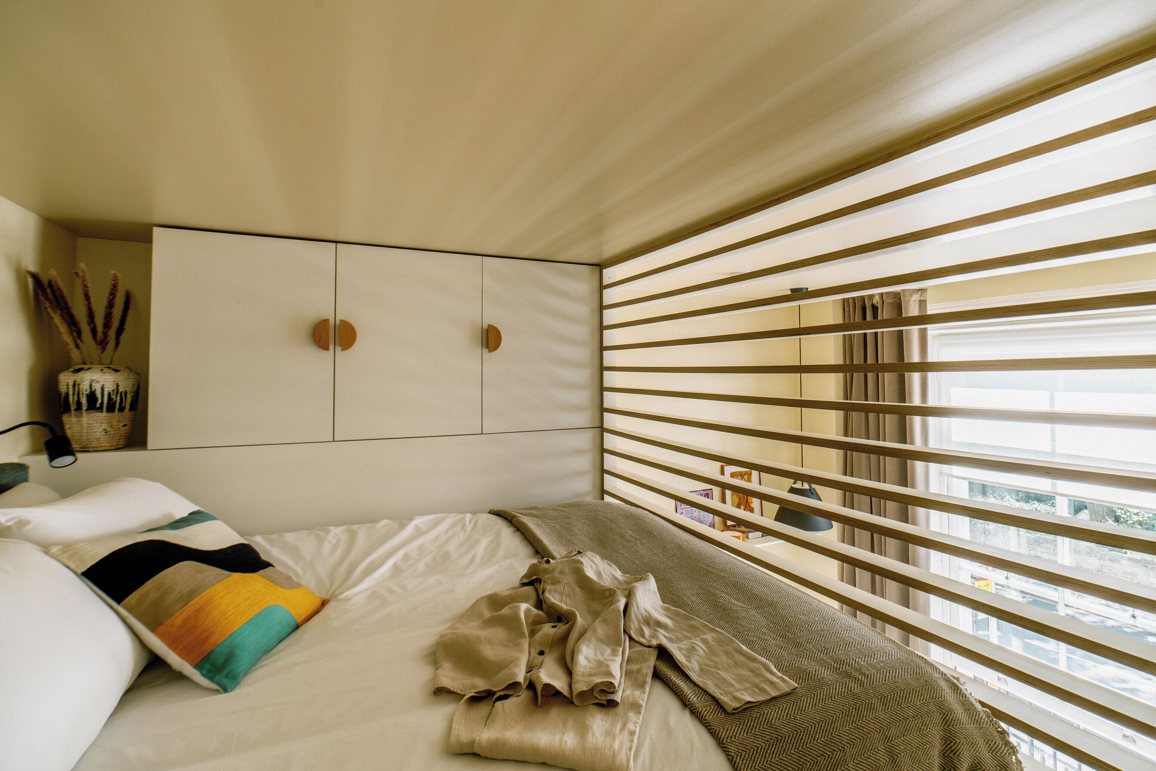 A bedroom with a bed, a wardrobe, and a window with blinds.