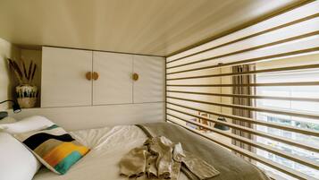 A bedroom with a bed, a wardrobe, and a window with blinds.