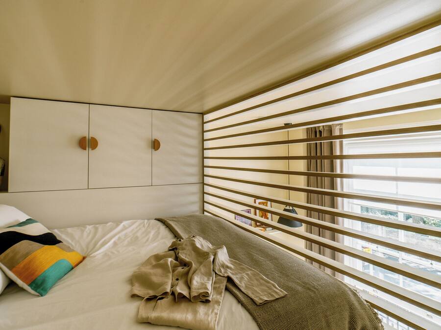 A bedroom with a bed, a wardrobe, and a window with blinds.