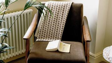 A chair with a book, a patterned throw, and a potted plant.