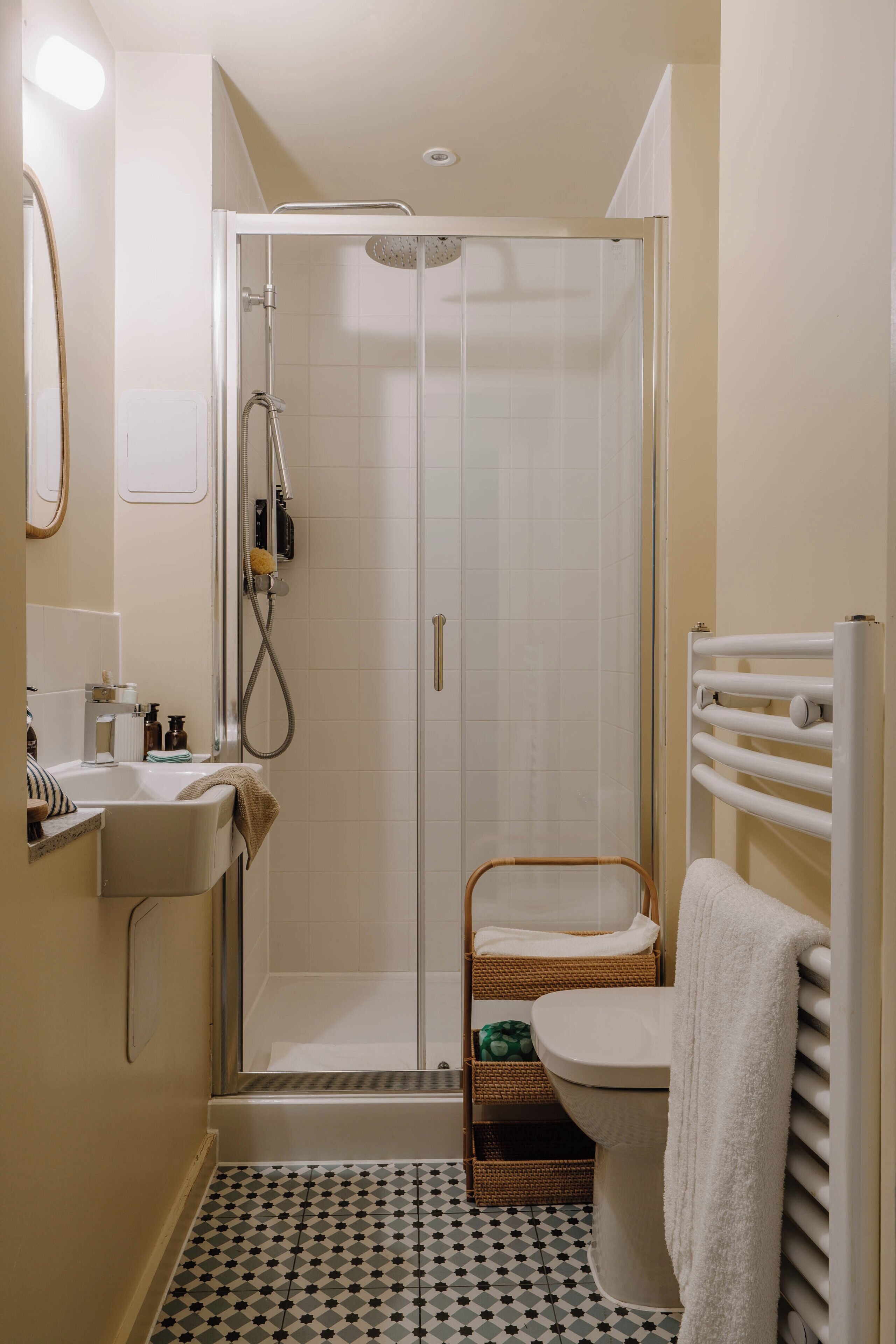 A bathroom with a shower, toilet, sink, and a towel rack.