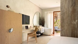 A modern hotel room with a bed, a desk with a laptop, a chair, a vanity with a mirror, and a view of the outdoors. - Vila Almesca (Porto Seguro)