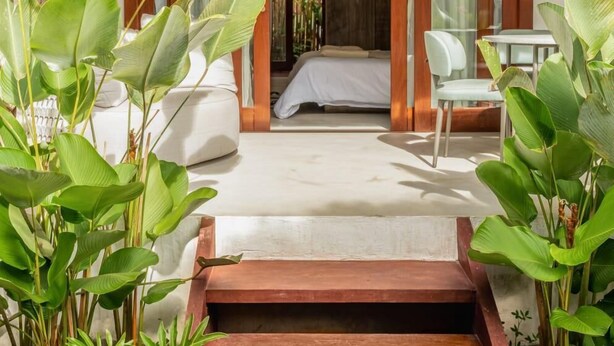 A modern hotel room with a large bed, a sitting area with a table and chairs, and a view of the interior. - Vila Almesca (Porto Seguro)