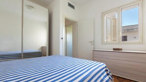 Un dormitorio con cama, cómoda, ventana y puerta.