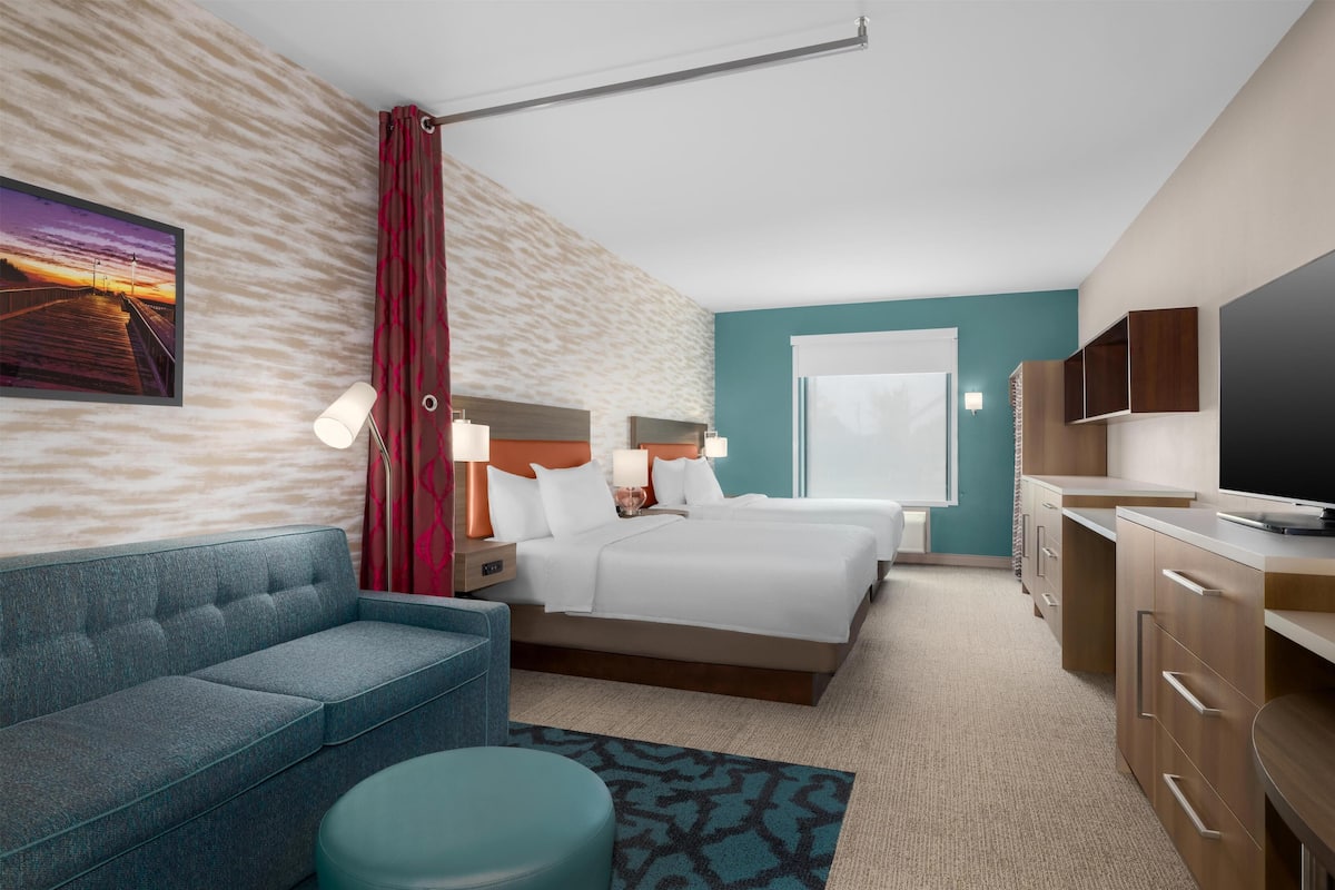 A hotel room with a bed, a sofa, a desk, and a TV.